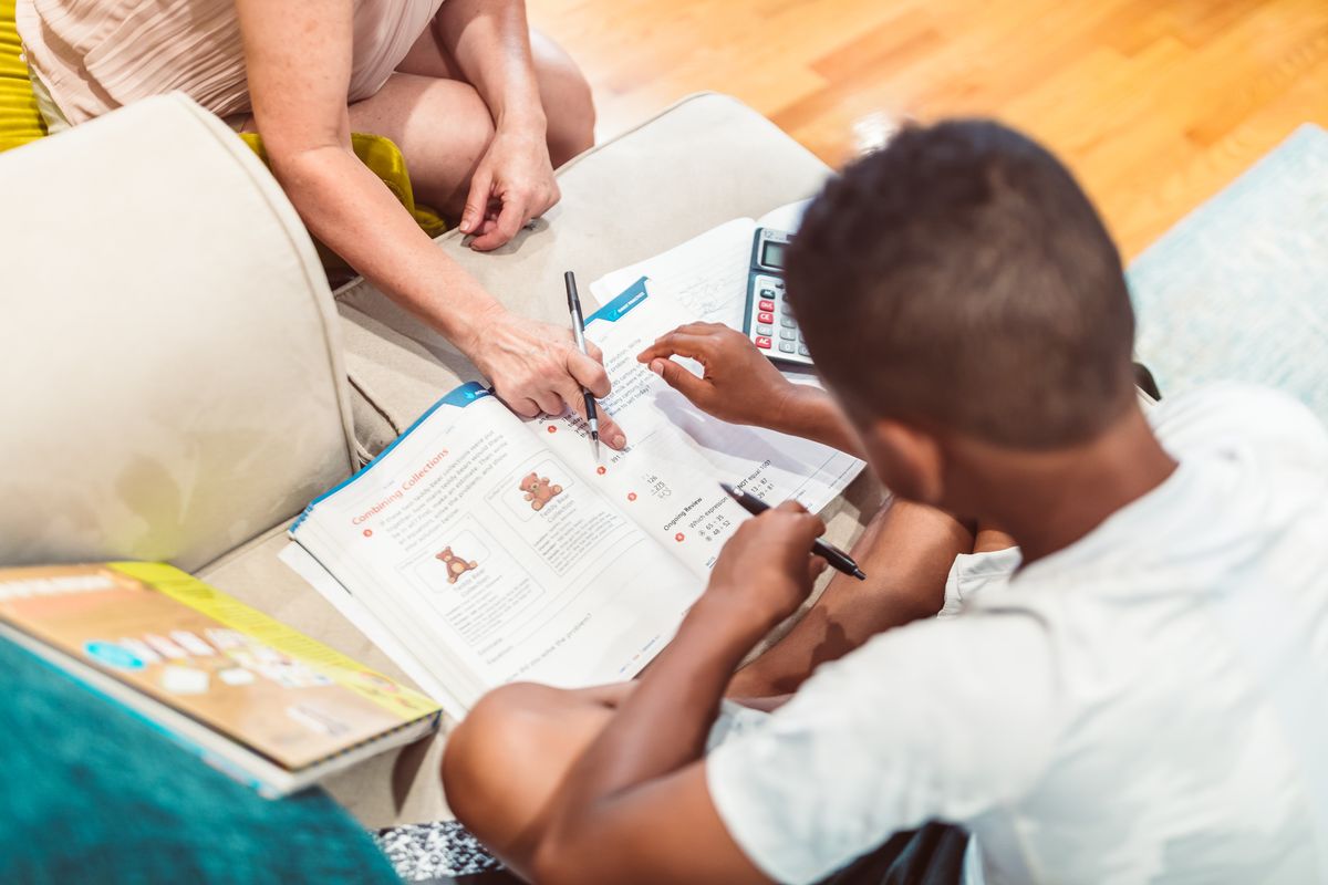 Une accompagnatrice aide un jeune garçon à faire ses devoirs de mathématiques